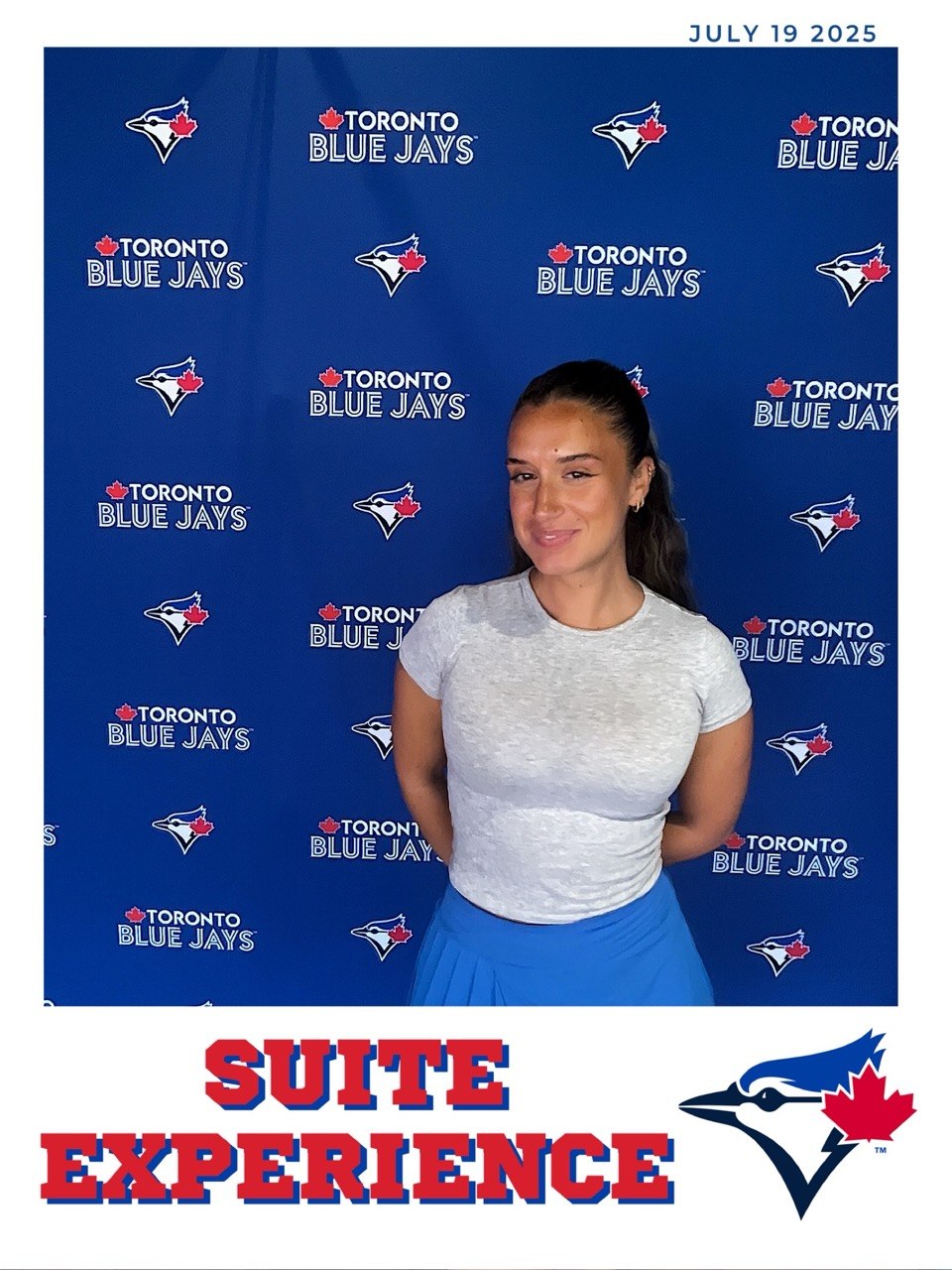 Guest posing in front of a Toronto Blue Jays Suite Experience photo booth backdrop