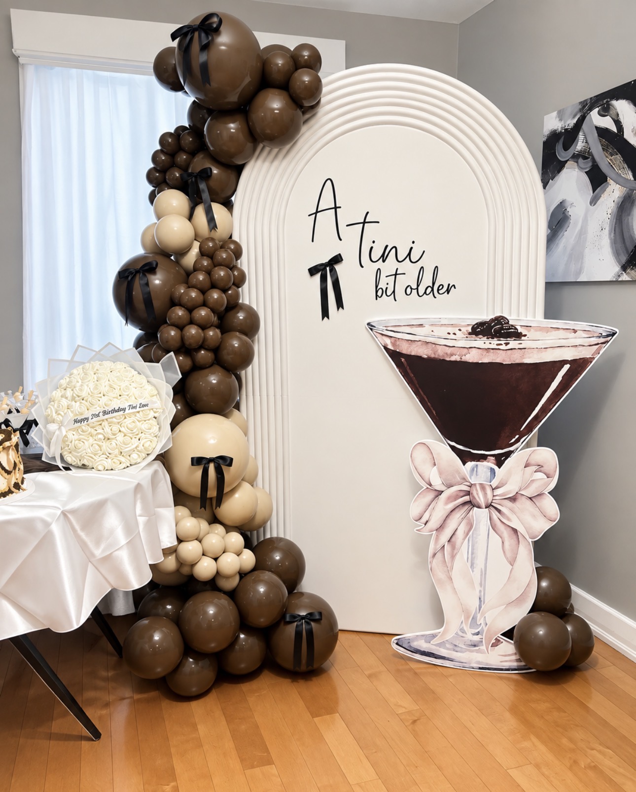 PartywithMY birthday setup with a cream ripple backdrop, chocolate balloons and a cocktail cutout